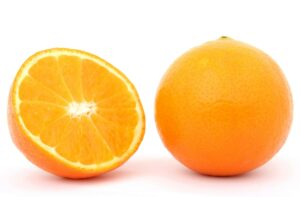 Close-up of a whole orange and a sliced half on white background, highlighting freshness.